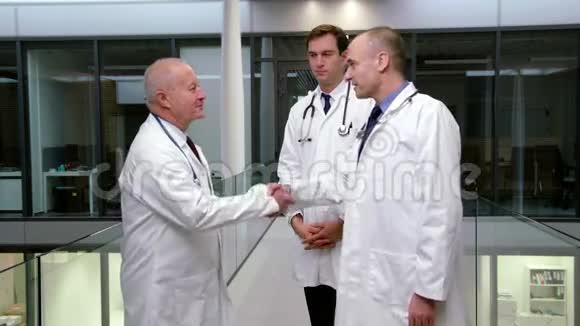 医生在走廊里握手时相互交流视频的预览图