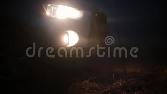 低角度车前灯在夜间开美丽的神秘景色模糊的bokeh黑暗背景抽象镜头视频的预览图