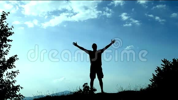 留在山顶上的剪影青年举起双手作为成就成功和喜悦的标志概念视频的预览图