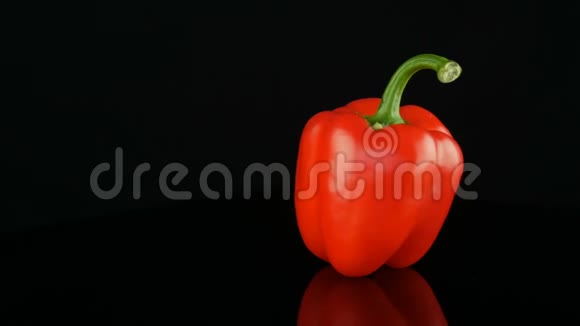 美丽的大熟红色甜椒辣椒在镜面和黑色背景上旋转视频的预览图