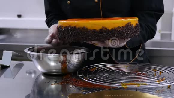 一个糖果师用巧克力片装饰橙色蛋糕的边缘并把它放在相机前的盘子里视频的预览图