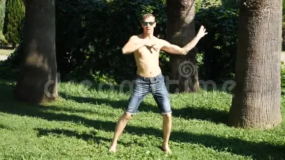 一个年轻快乐的家伙赤裸的躯干跳舞现代芭蕾和步行在一个夏季公园慢分子视频的预览图