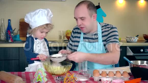 可爱的父亲和她兴奋的可爱女儿女孩在厨房里筛面粉视频的预览图