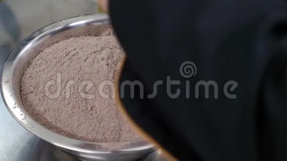 一个糖果师把几个鸡蛋打碎放进盛满黑麦面粉的碗里视频的预览图