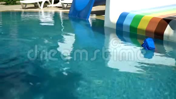 在阳光明媚的背景下有滑梯的游泳池水在桶漂浮着一个孩子视频的预览图