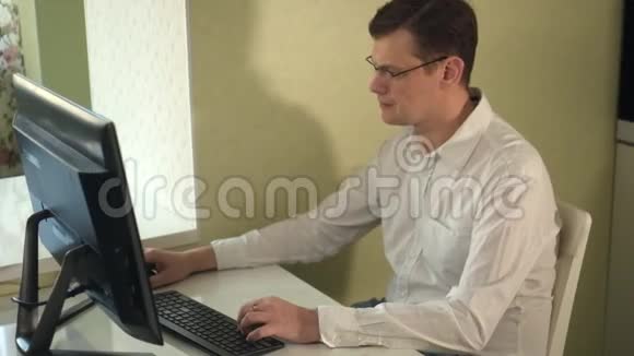 戴眼镜的严肃男子在电脑上工作视频的预览图