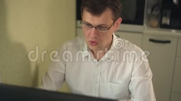 兴奋的尖叫的年轻人看着他的电脑屏幕举起双手胜利视频的预览图