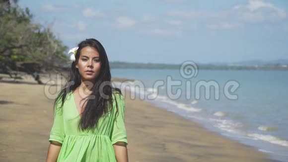 美丽的亚洲女孩穿着绿色连衣裙沿着海滩散步视频的预览图