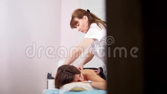 美容诊所一位年轻女子正在接受放松的背部按摩视频的预览图