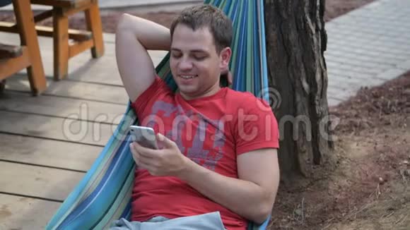 男人在吊床上放松时使用手机智能手机视频的预览图