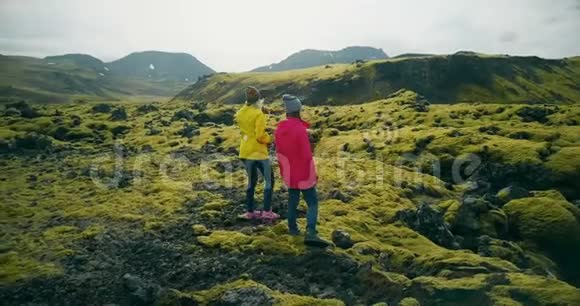 冰岛两名妇女在熔岩上行走的鸟瞰图游客欣赏风景探索领土视频的预览图