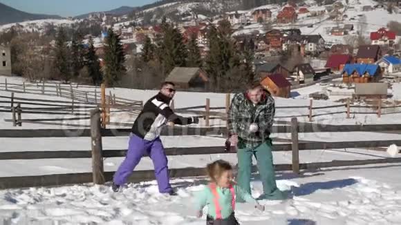 父母和孩子正在玩雪球户外享受温暖的阳光天气三男两女一男一女视频的预览图