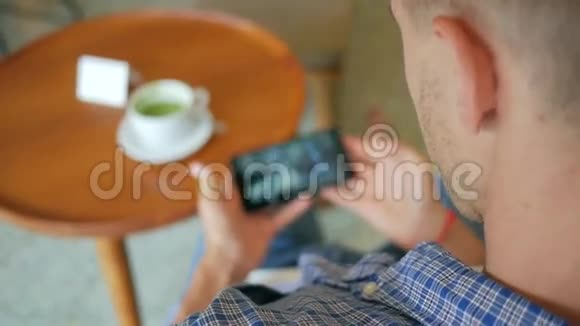 年轻英俊的男人在咖啡厅喝抹茶在手机上看视频HD慢动作生活方式视频的预览图