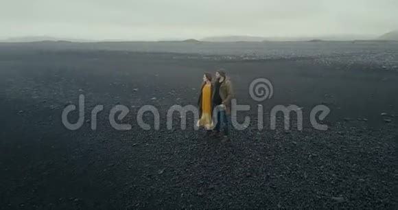 这对年轻的时髦夫妇在冰岛黑色的火山海滩上漫步男人和女人享受大自然视频的预览图