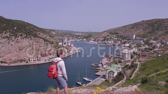 一个背着背包在山上欣赏风景的旅行者小城市景观视频的预览图