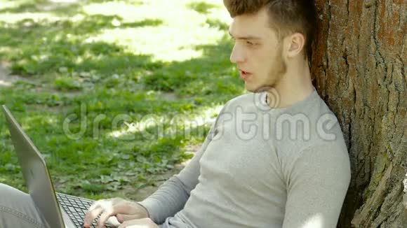公园里一个树底下的人用笔记本电脑工作视频的预览图