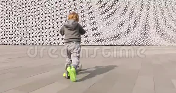 儿童骑绿色踢滑板车视频的预览图