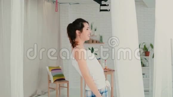 幸福的年轻女子穿着睡衣站在灯光公寓里微笑的女孩在早上玩得很开心慢动作视频的预览图