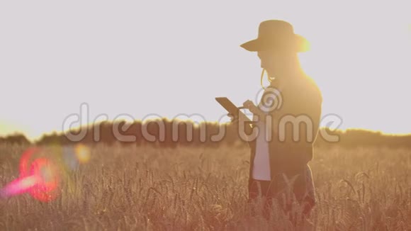 戴着帽子和格子衬衫的女农民摸着黑麦的芽和种子检查并将数据输入平板电脑视频的预览图