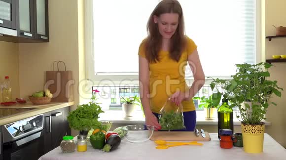 怀孕的妻子打开菜桌上的绿色沙拉叶盒视频的预览图