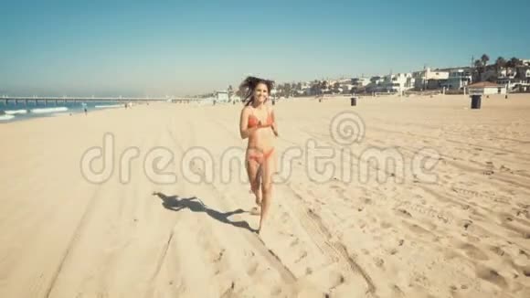 快乐的年轻女子在加州曼哈顿海滩跑步老式过滤器视频的预览图