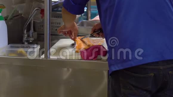 一家日本餐馆的厨师在一个开放的厨房里用手剁肉准备一个大鱼片视频的预览图