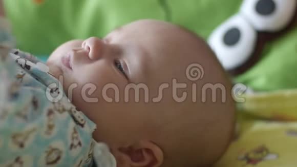 婴儿躺在玩具娃娃身上玩着玩具快乐的男孩在玩具娃娃特写镜头前微笑视频的预览图