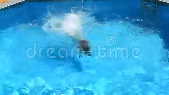 那孩子正在游泳池的蓝色水里游泳从上面看女孩在游泳池里潜入水中视频的预览图