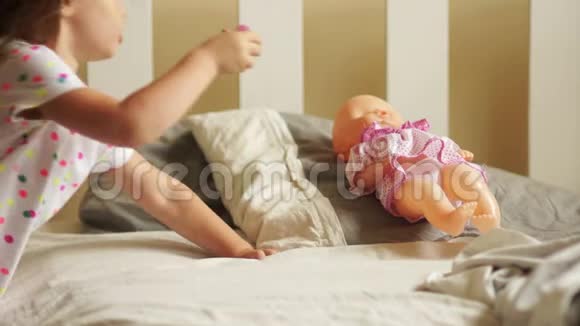 女孩在玩娃娃她让她睡觉给她一个奶嘴快乐的童年幼儿游戏妈妈视频的预览图