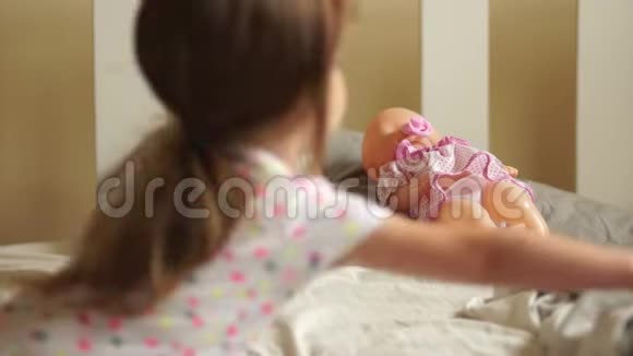 一个女孩把她的娃娃放在床上她小心翼翼地用毯子盖住它幼儿游戏母亲女儿视频的预览图