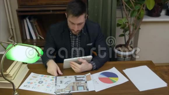 年轻的设计师拿着平板电脑在桌上检查商业文件视频的预览图