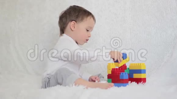 快乐的孩子在白色沙发上的彩色积木里玩耍视频的预览图