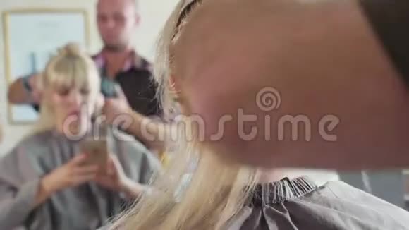 在美容院的男理发师给金发女郎梳头特写视频的预览图