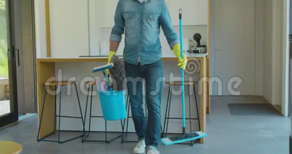 男人拿着拖把和塑料桶厨房里有刷子手套和洗涤剂视频的预览图