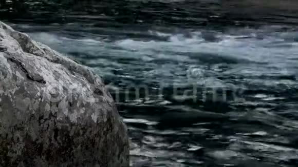 湍急的河水冲过一大块巨石流经森林视频的预览图