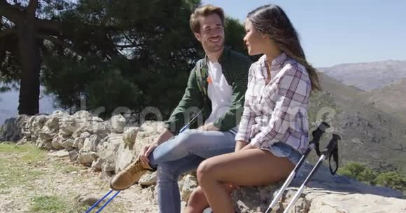 年轻夫妇坐在山上的岩石上视频的预览图