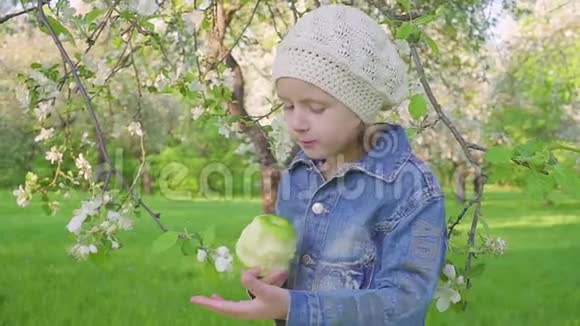 小女孩在开花的花园里吃绿苹果视频的预览图