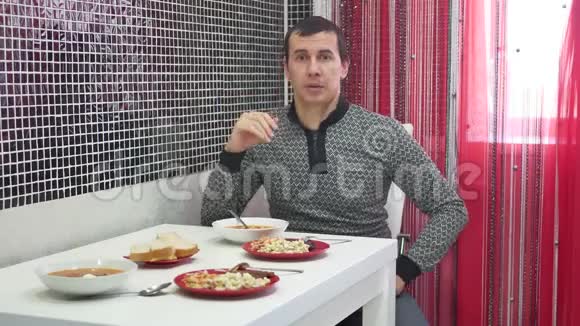 那个人在房子厨房的桌子旁说话男人在室内吃排骨和沙拉的生活方式视频的预览图