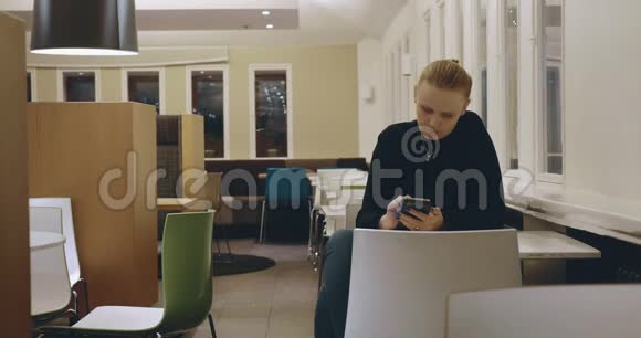 在咖啡馆里和手机度过孤独的夜晚的女人视频的预览图