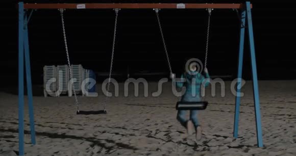 孩子晚上独自在沙滩上荡秋千视频的预览图