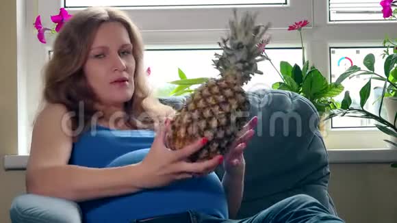 大肚婆抱着菠萝香蕉水果坐在沙发上视频的预览图