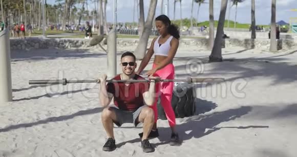 女人帮男人在海滩上锻炼视频的预览图