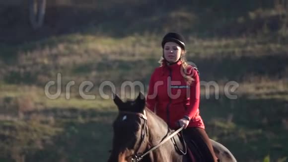 女人骑着马在绿色的田野上飞驰慢动作视频的预览图