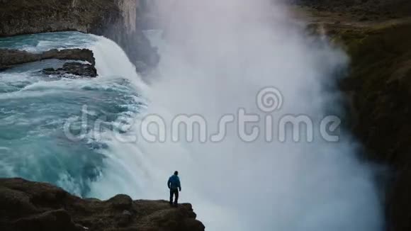 孤独的人站在山的边缘望着冰岛的古尔福斯瀑布的风景视频的预览图