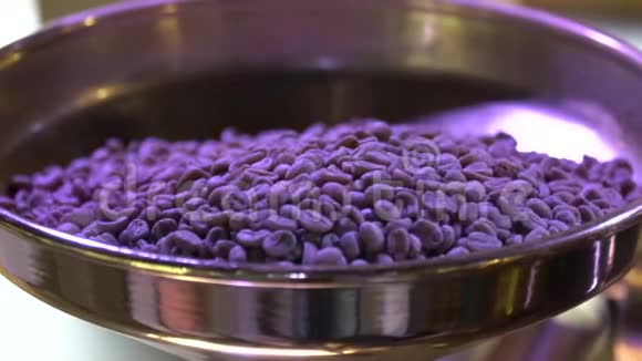 在紫外线下咖啡豆从碗中倒入烘焙咖啡机视频的预览图