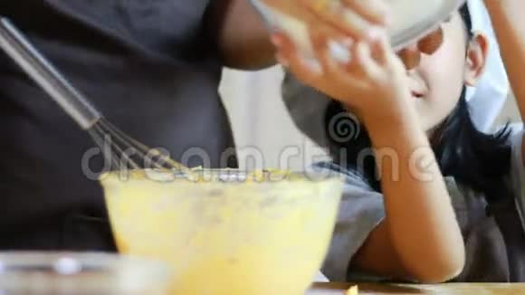 母亲和女儿的手在筛面粉和混合烘焙原料视频的预览图