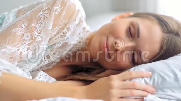 一位美丽的年轻女子在白色的房间里醒来视频的预览图