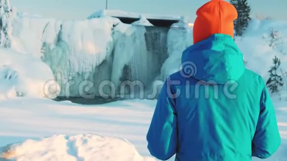 一个年轻的女孩拍了一张冰冻瀑布的照片在智能手机上拍照水流浮冰和冰柱视频的预览图