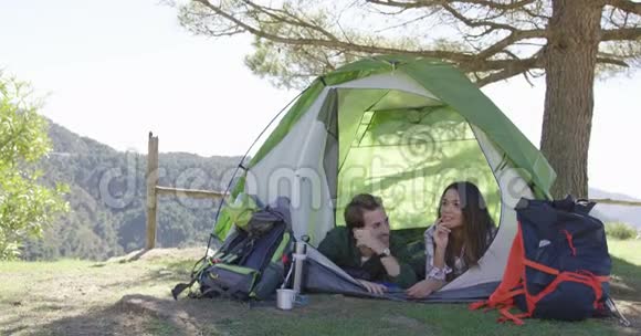 微笑的情侣躺在帐篷里聊天视频的预览图