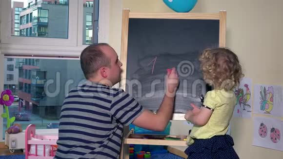 老师给小女孩用粉笔黑板写数字视频的预览图